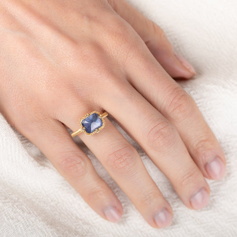 Gold ring with a blue tanzanite gemstone on a hand