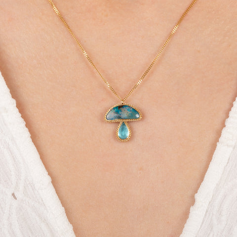 Gold necklace with mushroom pendant featuring boulder opal and aquamarine stones on a person