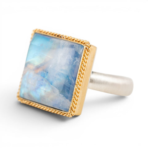 Gold and silver ring with a square moonstone on a white background