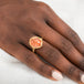 Gold ring with a sunstone stone on a person's finger against a neutral background