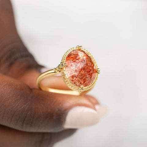 Gold ring with a sunstone stone held in hand