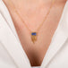 Gold necklace with a tanzanite gemstone on a person wearing a white top.