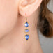 Gold earrings with tanzanite stones worn by a person