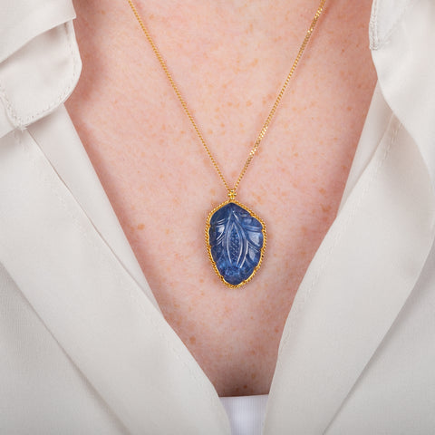 Handcrafted gold necklace featuring a leaf-shaped tanzanite on a person