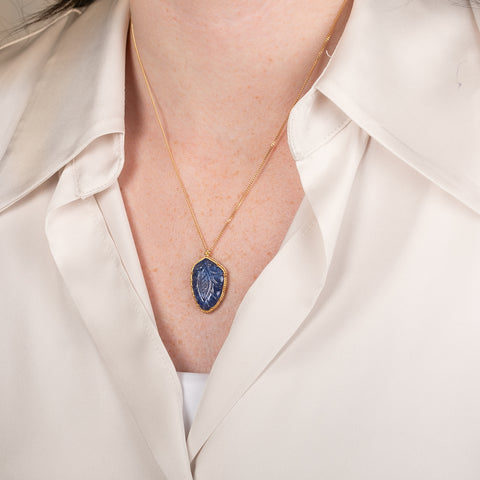 Handcrafted gold necklace featuring a leaf-shaped tanzanite on a person