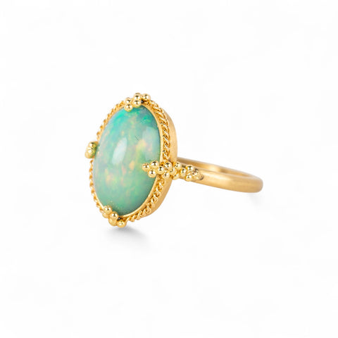 Gold ring with an Ethiopian opal gemstone on a white background