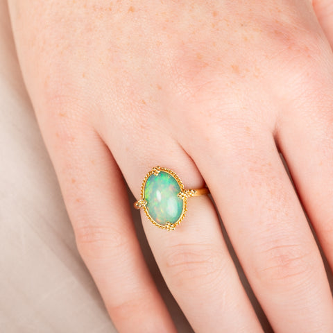 Gold ring with an Ethiopian opal gemstone on a hand