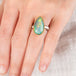 Hand wearing an Ethiopian opal teardrop ring with gold bezel and silver band
