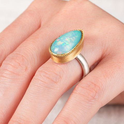 Hand wearing an Ethiopian opal ring with 18k gold bezel and sterling silver band
