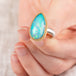Hand holding an Ethiopian opal ring with 18k gold bezel and sterling silver band