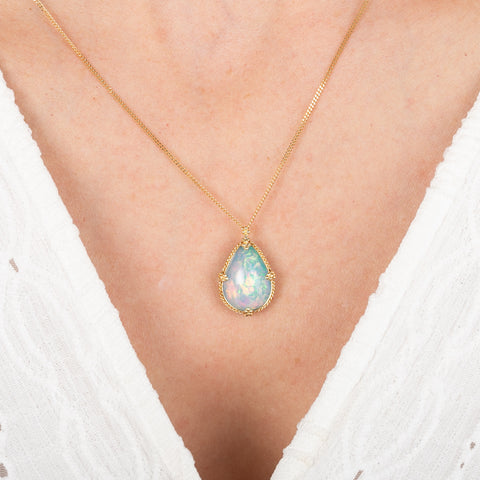 Ethiopian Opal teardrop pendant necklace on a person wearing a white top.