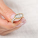 Gold and silver ring with a topaz gemstone held by a hand against a light background