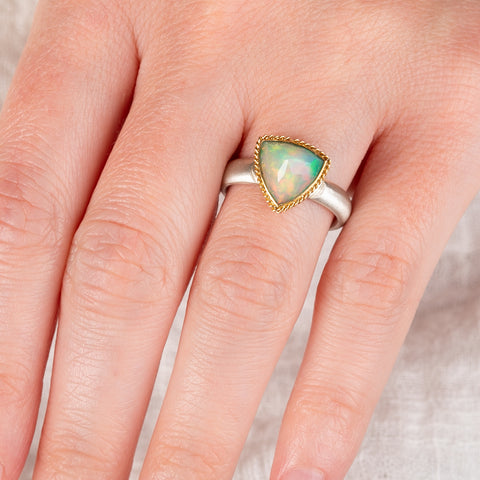 Hand wearing an Ethiopian opal ring with 18k gold bezel and sterling silver band