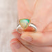 Close up of hand holding an Ethiopian opal ring with 18k gold bezel and sterling silver band