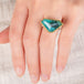 Hand wearing a Peruvian opal ring with gold bezel and sterling silver band