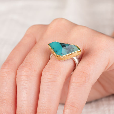 Close up of a Peruvian opal ring with gold bezel and sterling silver band