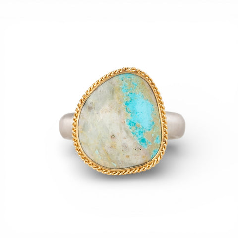 Gold and silver ring with a turquoise stone on a white background