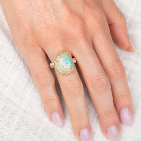 Gold and silver ring with a turquoise stone on a hand