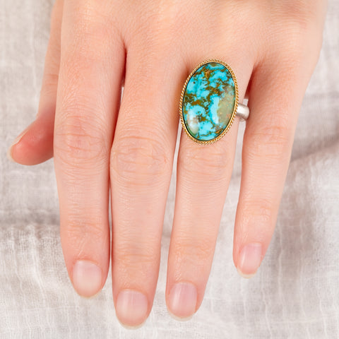 Hand wearing a handmade turquosie ring with a gold bezel and sterling silver band