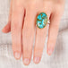 Hand wearing a handmade turquosie ring with a gold bezel and sterling silver band