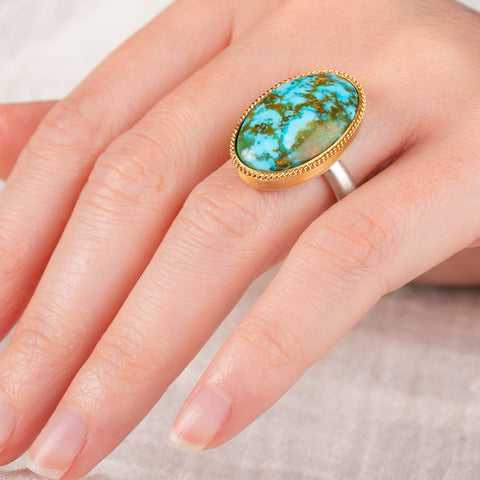 Hand wearing a handmade turquosie ring with a gold bezel and sterling silver band