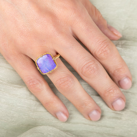 Gold ring with a purple boulder opal stone on a hand