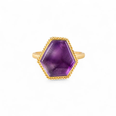 Gold ring with an amethyst gemstone on a white background