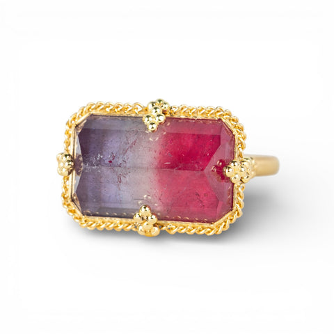 Gold ring with a faceted watermelon tourmaline gemstone on a white background