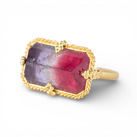 Gold ring with a faceted watermelon tourmaline gemstone on a white background