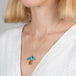 Necklace with a colorful mushroom pendant worn by a person in a white outfit