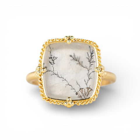 Ring with gold band and dendritic quartz stone stone on a white background
