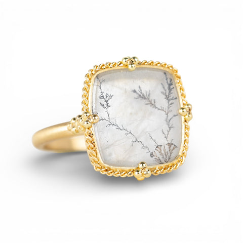 Ring with gold band and dendritic quartz stone stone on a white background