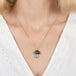 Gold necklace with a mushroom pendant featuring boulder opal and aquamarine stones on a person