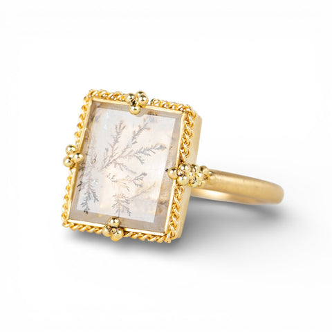 Gold ring with a dendritic quartz stone featuring natural inclusions on a white background