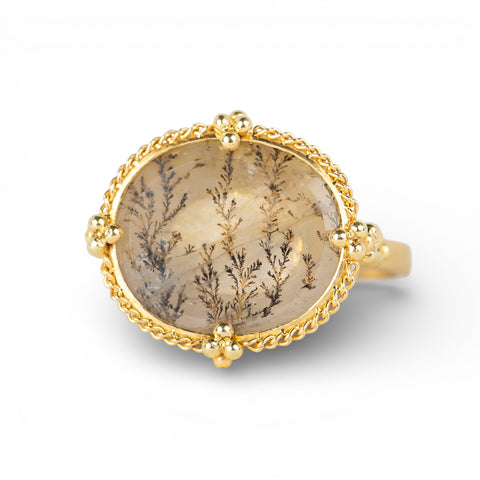 Gold ring with a dendritic quartz stone and intricate design on a white background