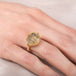 Gold ring with a dendritic quartz stone and intricate design on a hand