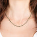 Gold necklace with emerald gemstones on a person's neck