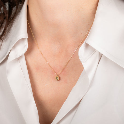 Gold necklace with a yellow diamond pendant worn by a person in a white shirt.