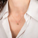 Gold necklace with a yellow diamond pendant worn by a person in a white shirt.