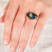 A hand wearing a Yowah nut opal ring with an 18k gold bezel and sterling silver band