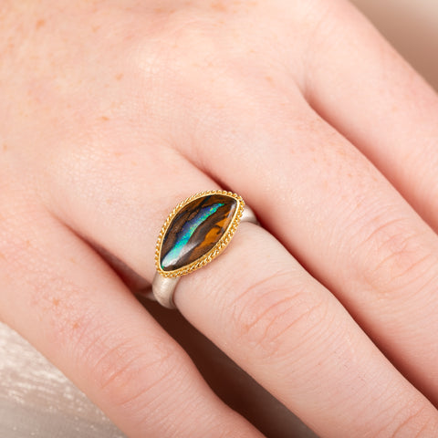 Yowah nut opal ring with a gold setting and silver band on a person's finger