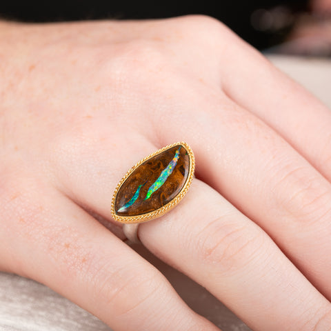 Ring with an opalized wood stone, gold setting and silver band on a hand