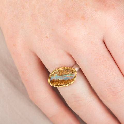 Ring with an opal stone, gold setting and silver band on a hand