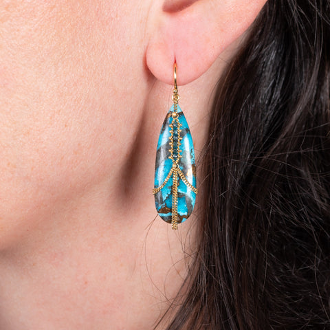 Draped dark matrix turquoise earrings on a model