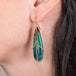 Draped petrified wood blue opal earrings on a model