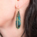 Draped elongated petrified wood blue opal earrings on a model