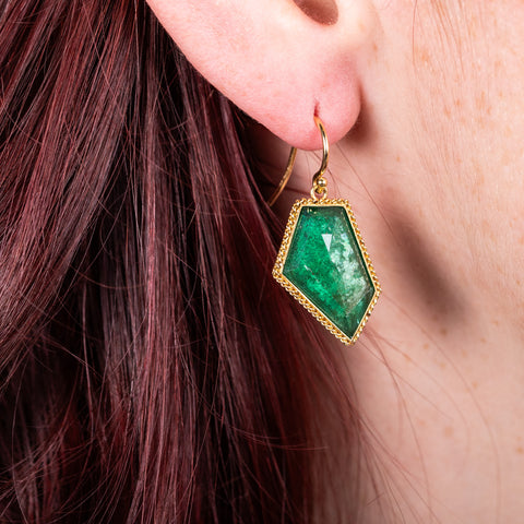 Geometric emerald earrings on model side view