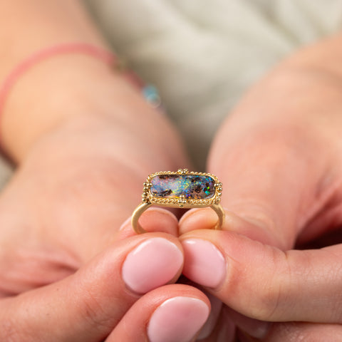 Boudler opal ring held by model