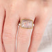 A person wears a handcrafed ring featuring a mexican opal gemstone in an 18k gold setting with a sterling silver band