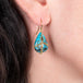 Petite draped turquoise earrings on a model